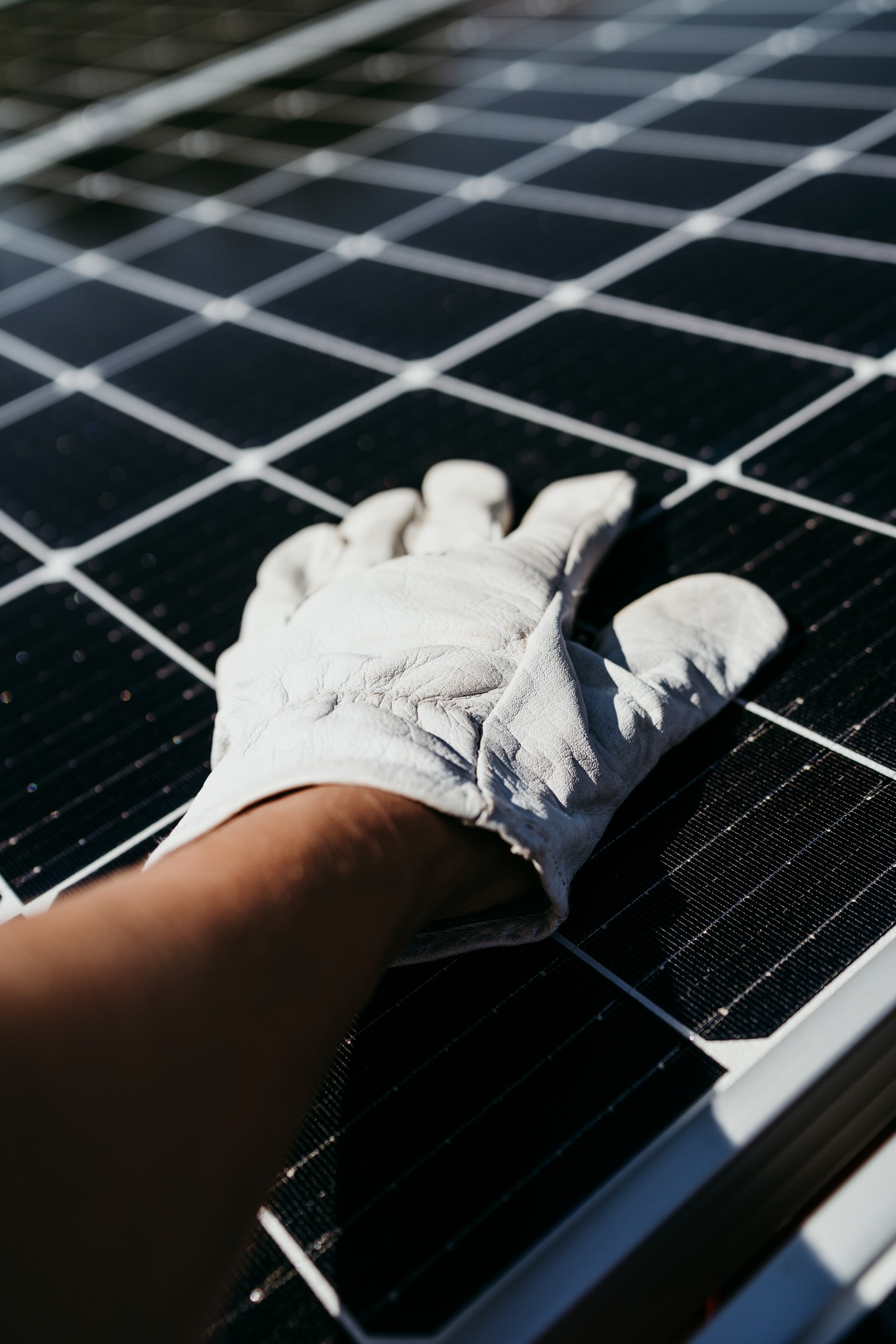 hand of Technician touching solar panels on house roof for self consumption energy. Renewable energy